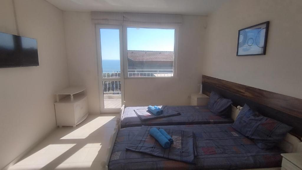 a bedroom with two beds and a large window at Antorino in Balchik