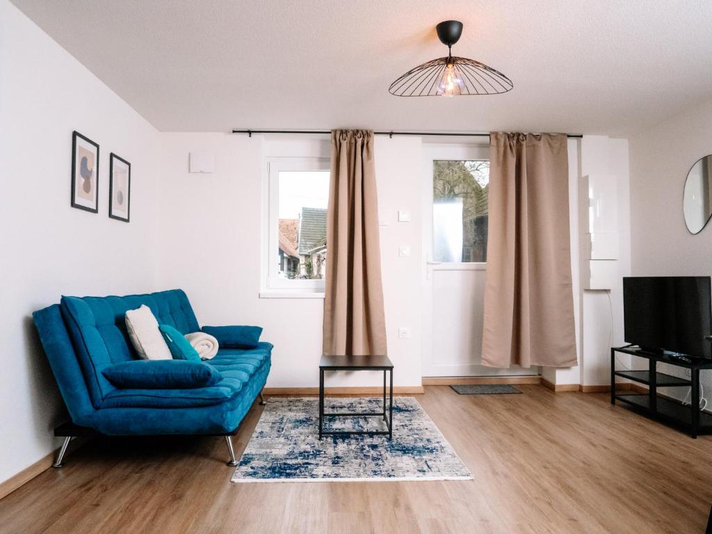 a living room with a blue couch and a television at La Suite Cosy in Roppenheim