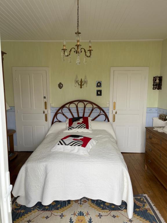 Un dormitorio con una cama con sábanas blancas y una lámpara de araña. en Chambre d'Hôtes Lacapelle Del Fraisse en La Capelle-del- Fraisse