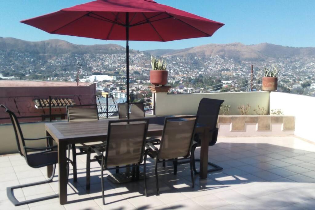 een tafel en stoelen met een rode parasol op een dak bij Fabulous City View Apartment in Oaxaca City