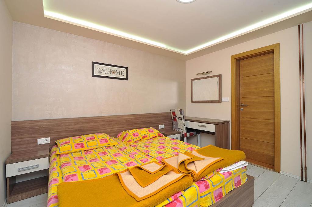 a bedroom with a large bed with a yellow blanket at Vila Mina in Zlatibor