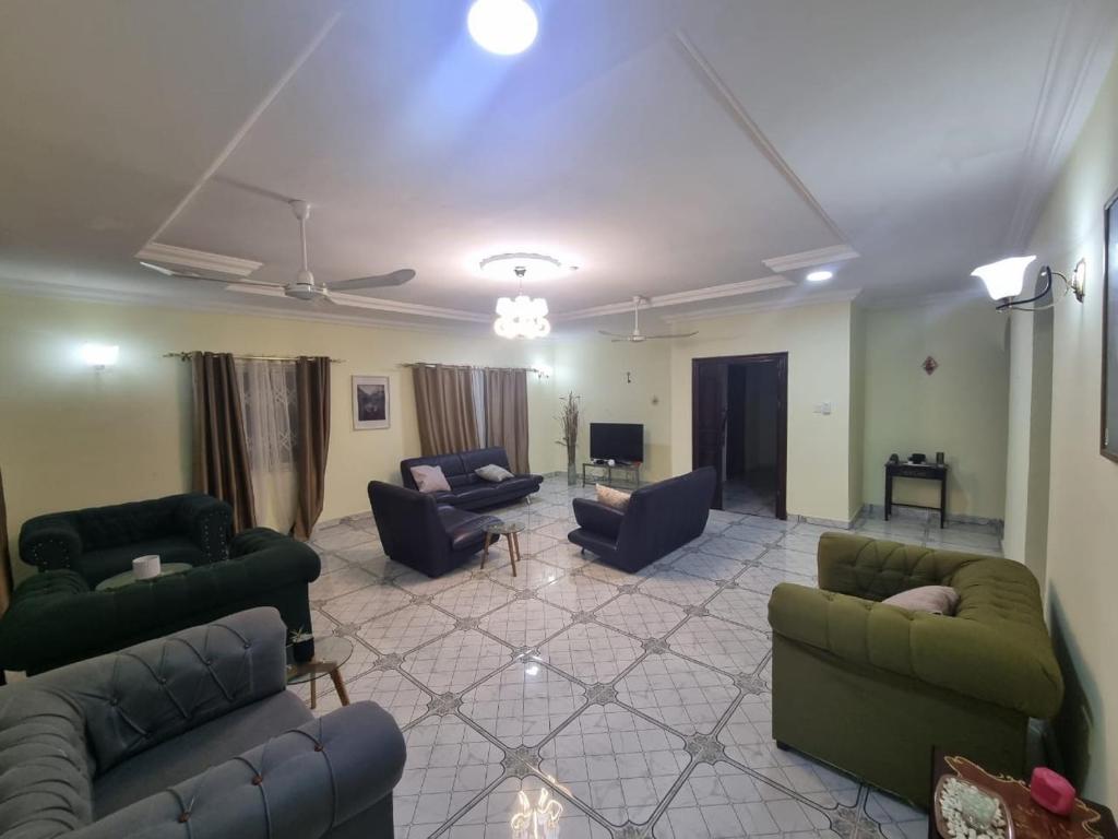 a living room with couches and chairs and a tv at B's Classic and Cozy Apartments in Cape Coast