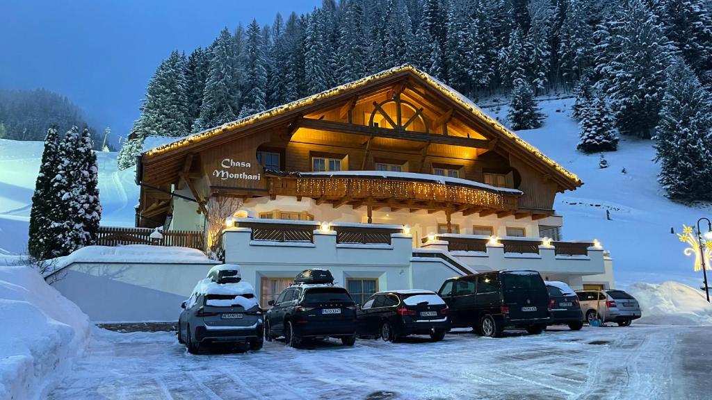 een groot gebouw met auto's geparkeerd in de sneeuw bij Chasa Monthani in Ischgl