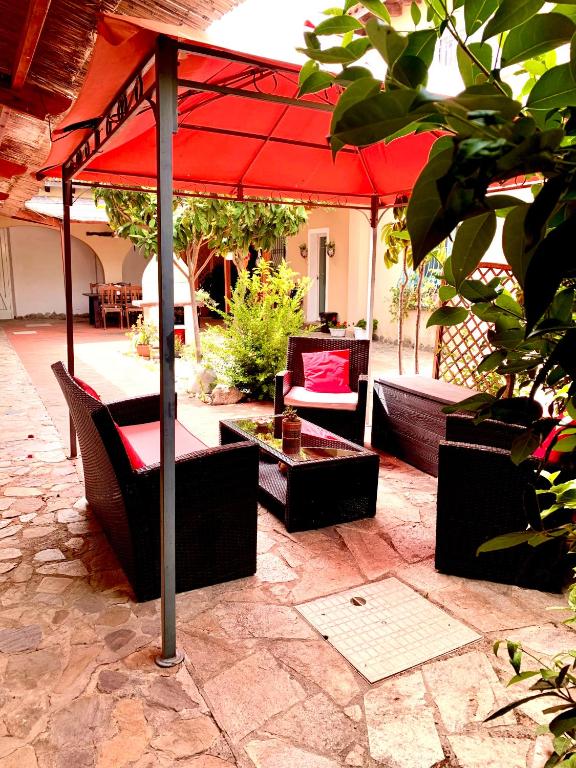 a patio with a red umbrella and chairs and tables at LA DEPENDANCE in Su Forti
