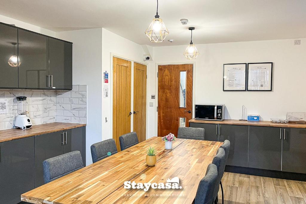 a kitchen and dining room with a wooden table at Stylish 10 Bedrm House, Fast Wifi, Free Parking in Manchester