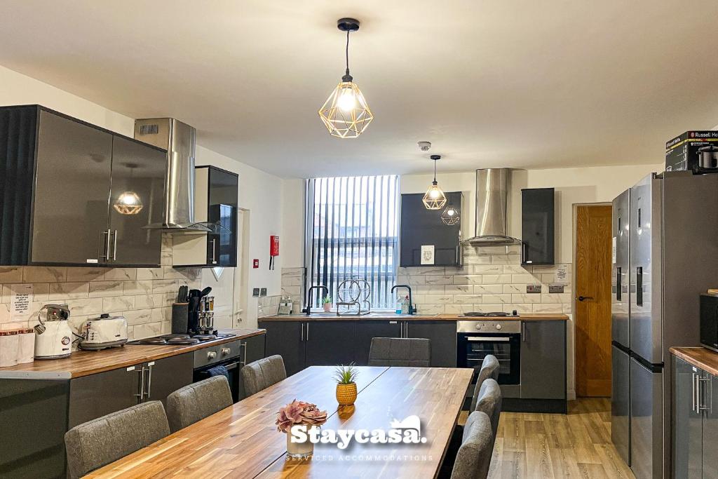 a large kitchen with a wooden table and a dining room at Stylish 10 Bedrm House, Fast Wifi, Free Parking in Manchester