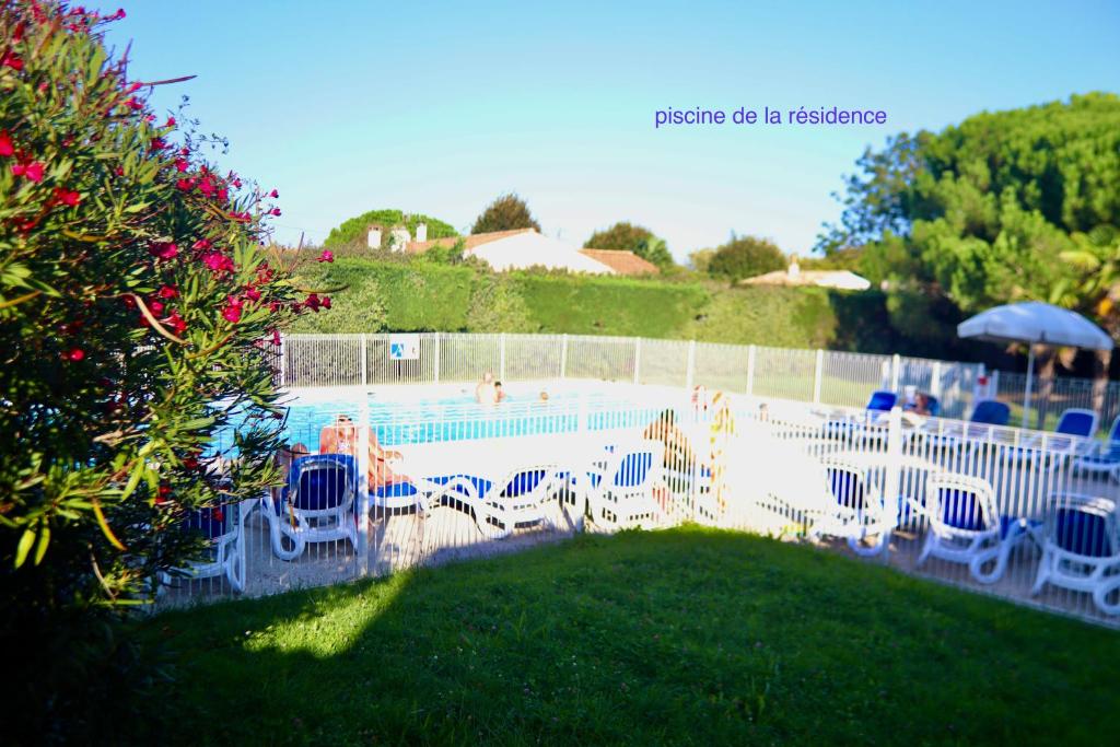 einen Pool mit Stühlen und einem Sonnenschirm in der Unterkunft Près des claires in Le Château-dʼOléron