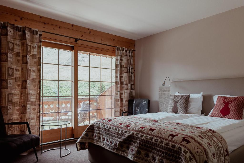 um quarto com uma cama e uma grande janela em Hotel L'Etable em Les Crosets