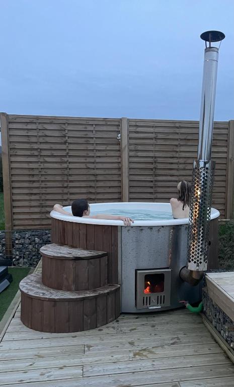 a couple of people laying in a hot tub with a fireplace at TY COAT - Maison neuve avec vue mer, piscine et bain nordique in Saint-Pabu