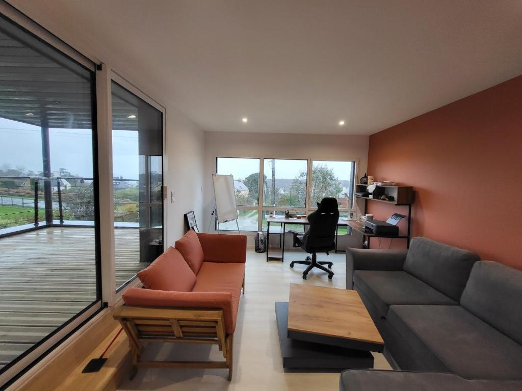 a living room with a couch and a table with a desk at TY COAT - Maison neuve avec vue mer, piscine et bain nordique in Saint-Pabu