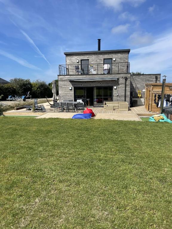 a house with a lawn in front of it at TY COAT - Maison neuve avec vue mer, piscine et bain nordique in Saint-Pabu