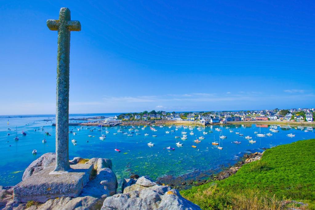 a cross on a rock with boats in the water at TY COAT - Maison neuve avec vue mer, piscine et bain nordique in Saint-Pabu