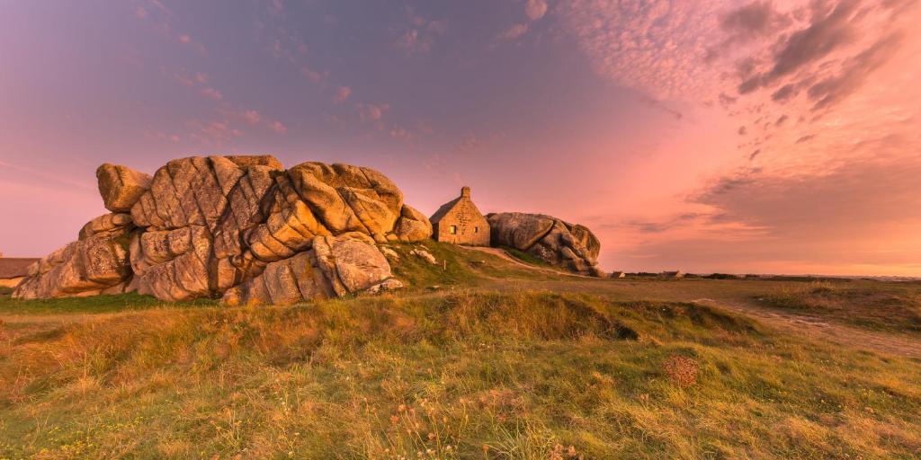 a house on top of a large rock in a field at TY COAT - Maison neuve avec vue mer, piscine et bain nordique in Saint-Pabu