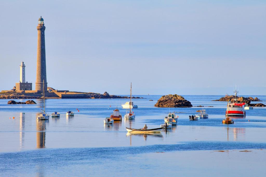 a group of boats in a body of water with a lighthouse at TY COAT - Maison neuve avec vue mer, piscine et bain nordique in Saint-Pabu
