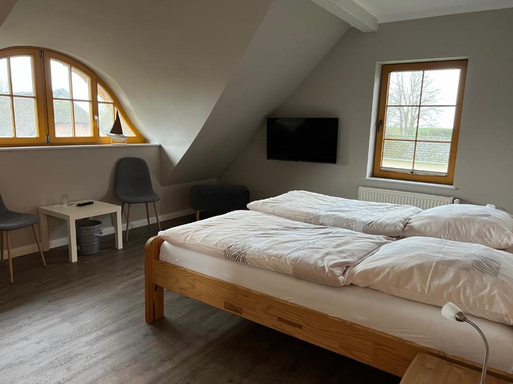 a bedroom with a bed and a tv and two windows at Gästehaus-Erbst in Loxstedt