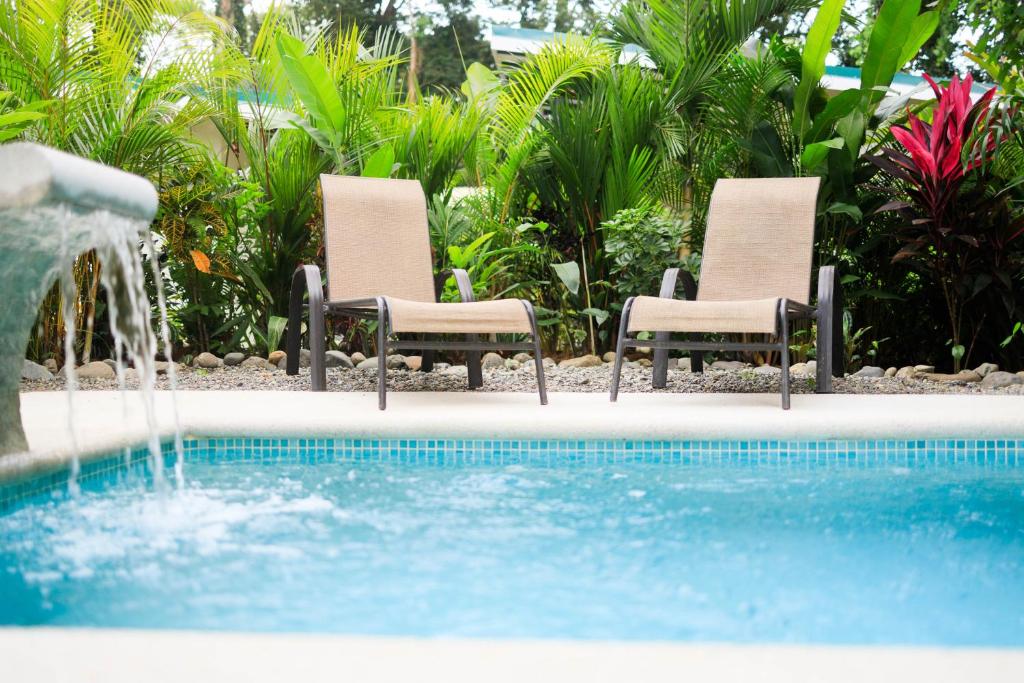 two chairs and a swimming pool with a fountain at Villas Mar y Coral in Puerto Viejo