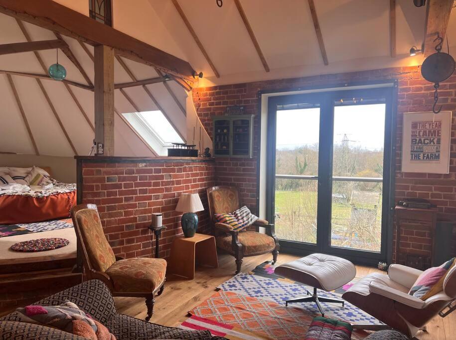 uma sala de estar com cadeiras e uma parede de tijolos em Unique luxury self-contained oast apartment em Kent