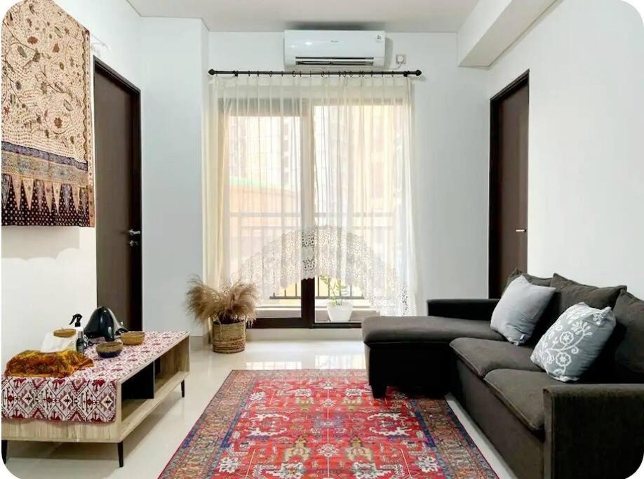 un soggiorno con un divano e un tavolo di Apt Transpark Cibubur 2 BR With Wi-Fi & Pool a Kalimanggis