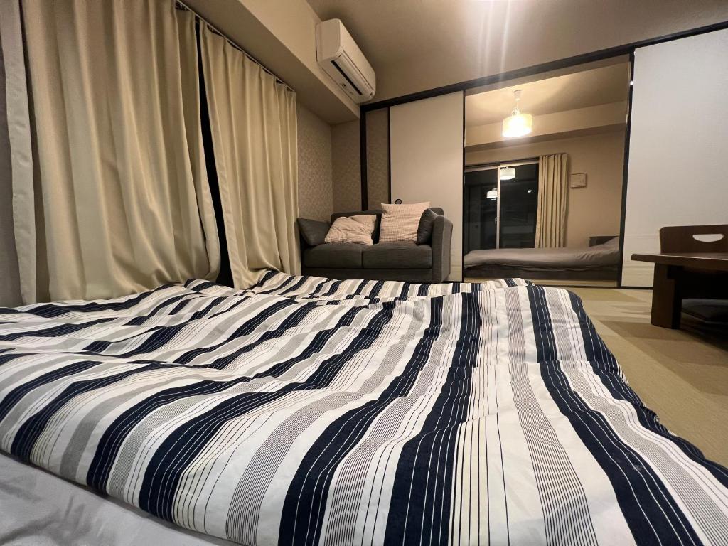 a bedroom with a striped bed with a chair in the background at 心斎橋-道頓堀の宿 ー南海難波徒歩10分以内 in Osaka