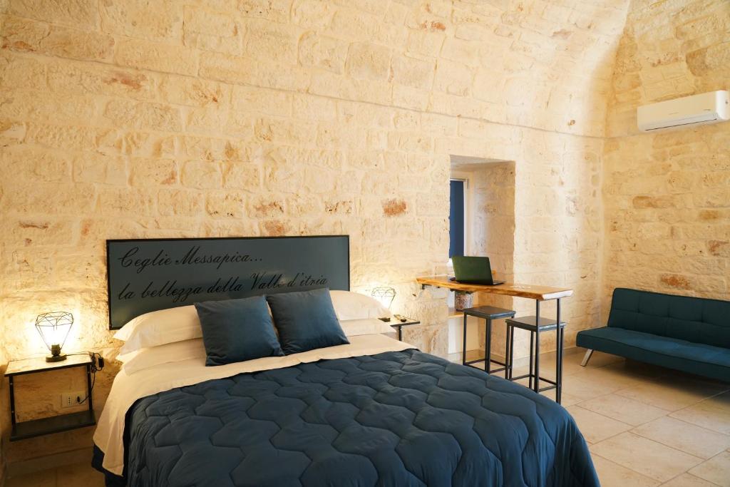 ein Schlafzimmer mit einem Bett in einem Zimmer mit einer Steinmauer in der Unterkunft La Suite del Conte - STORIA, CONFORT ed ELEGANZA in Ceglie Messapica