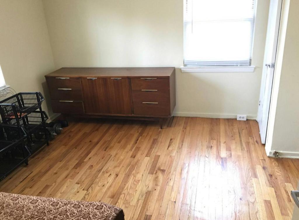 un soggiorno con pavimento in legno e cassettiera. di Suite 55 a Elmwood Park