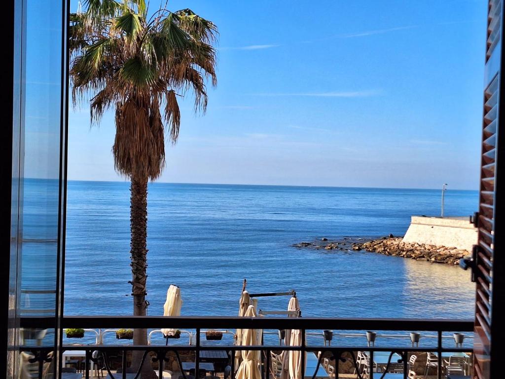 a view of the ocean and a palm tree from a balcony at Mowita in Civitavecchia