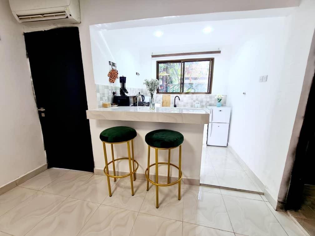 a kitchen with a counter with two green stools at Retreat Homes in Dar es Salaam