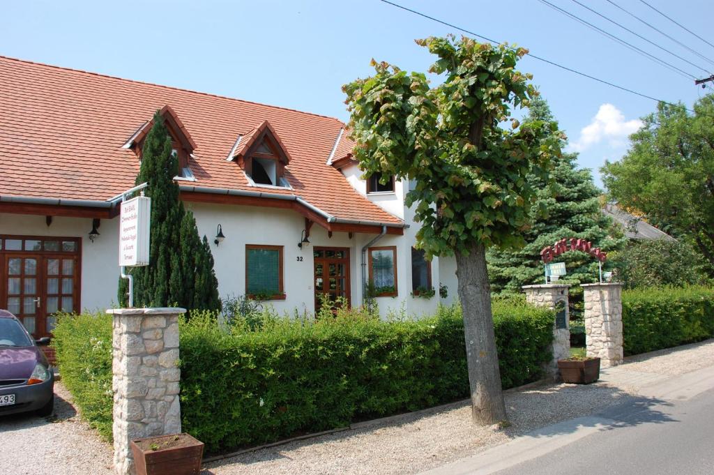 Una casa blanca con un árbol delante. en Emil porta, en Balatongyörök