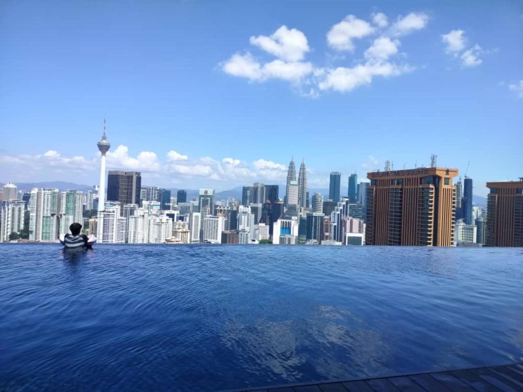 a person sitting in a infinity pool with a city skyline at LUCENTIA KUALA LAMPUR in Kuala Lumpur
