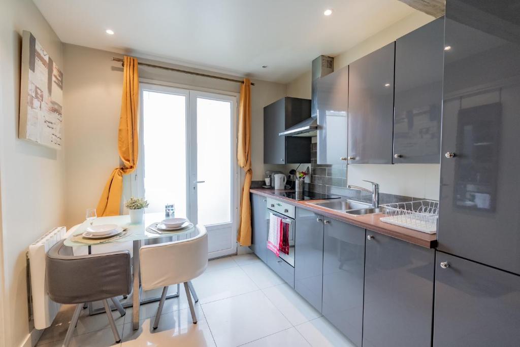 une cuisine avec un évier et une table avec des chaises dans l'établissement STUDIO, à Le Thillay