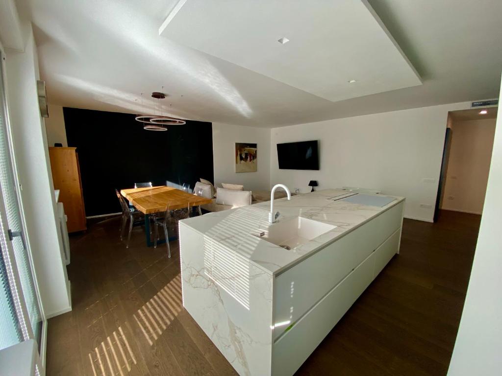 een witte keuken met een wastafel en een tafel bij Casa Perini - Luxury Apartment in Trento