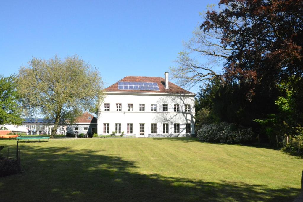 a large white house with a large grass yard at B & B Landhuis Ter Velt in Melle