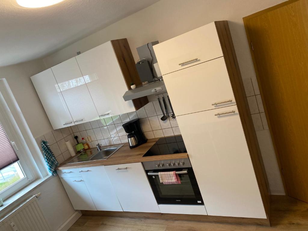 a kitchen with white cabinets and a stove top oven at FeWo WIEKO Plauen Leibnizstr. H3, 2. OG rechts in Plauen