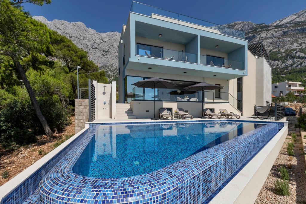 a house with a swimming pool in front of a house at Luxury Villa Bašak with Infinity Pool and Sea View in Makarska