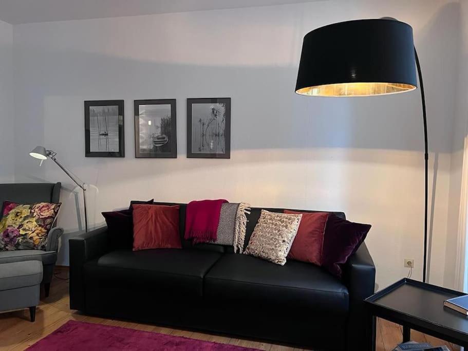 a living room with a black couch and a lamp at seeglueck SEELIEBE Stadtlage in Konstanz