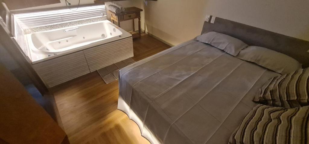 a bedroom with a bed and a sink at Pousada Dunas - Suítes com HIDROMASSAGEM no coração da Vila in Itaúnas