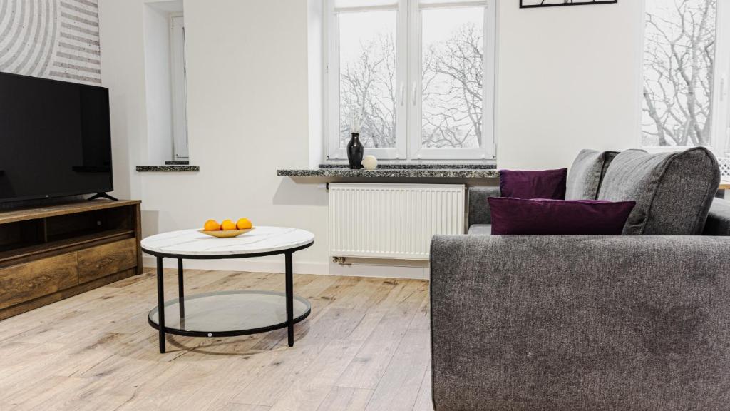 a living room with a couch and a table with oranges on it at VacationClub - Old Town Apartament 15 in Kłodzko