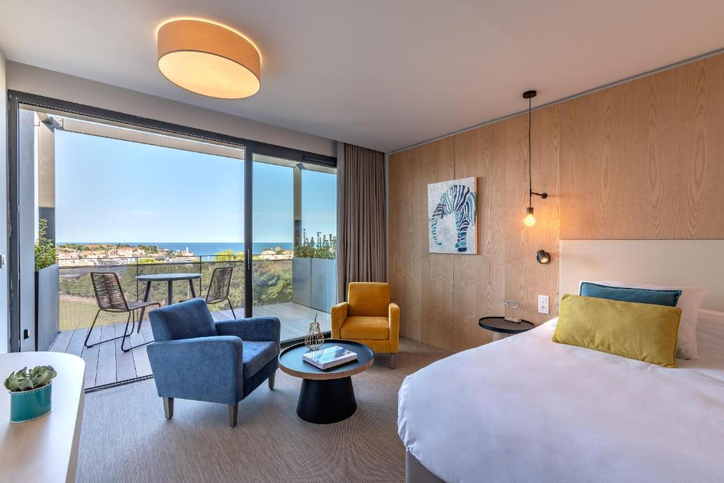 um quarto de hotel com uma cama e uma sala de estar em Les Jardins Du Cèdre em Port-Vendres