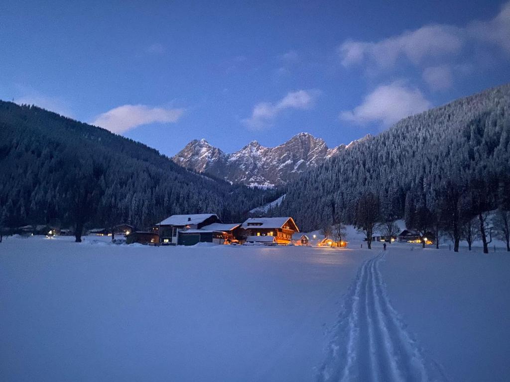 a snow covered field with a house in the distance at Sattlehnerhof in Ramsau am Dachstein