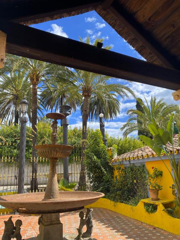 a fountain in a courtyard with palm trees at Cortijo La Saleta Banús in Marbella