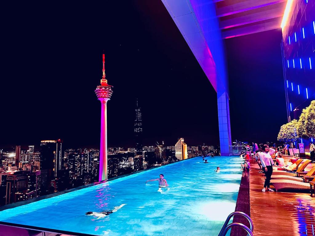 a swimming pool with people in the city at night at Platinum suites by BLUE SKY in Kuala Lumpur