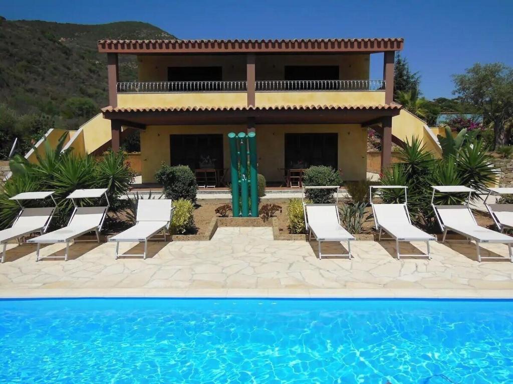 a villa with a swimming pool in front of a house at Appartamento in splendido e riservato villaggio, marina di Tertenia in Tertenìa