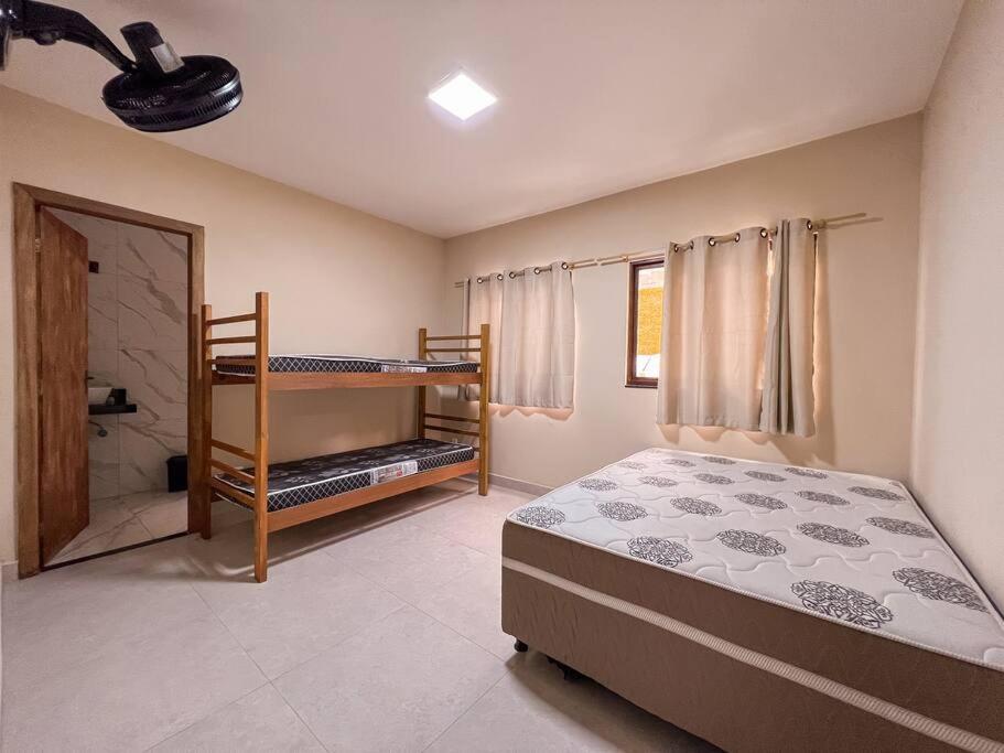 a bedroom with a bed and a bunk bed and a bathroom at Sítio com Piscina e Hidromassagem Confins in Confins