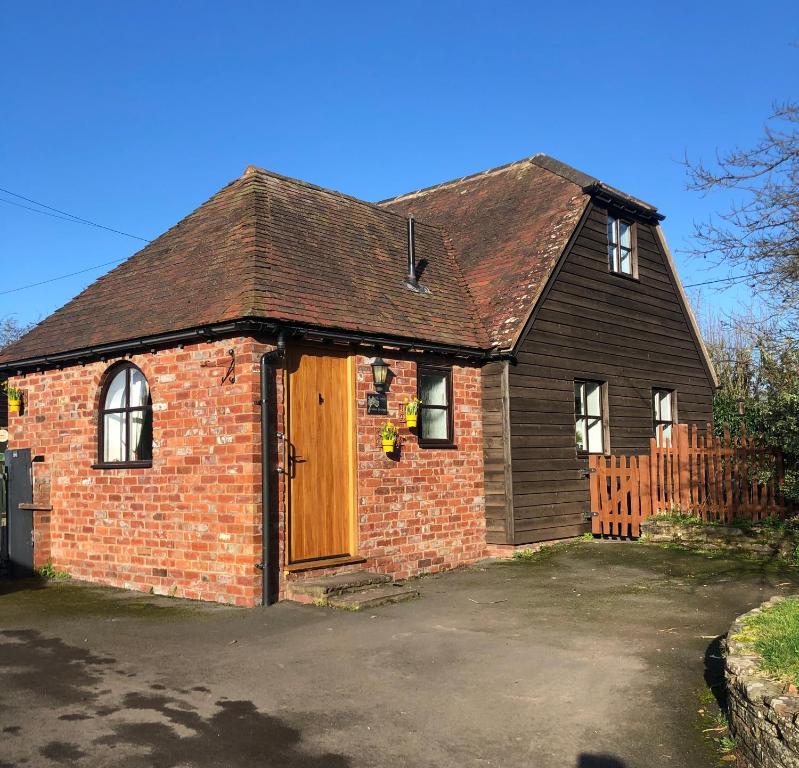 een oud bakstenen huis met een houten deur bij The Annexe at Walnut Tree Cottage in Hope under Dinmore