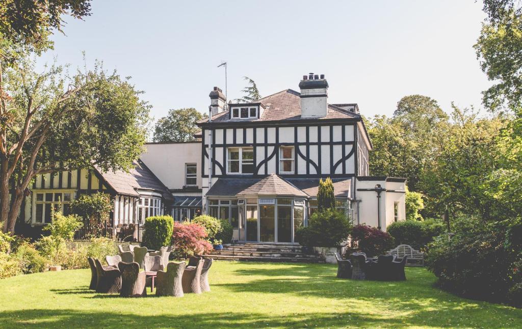 ein großes schwarz-weißes Haus mit Stühlen im Hof in der Unterkunft Brook Hall Hotel in Childer Thornton
