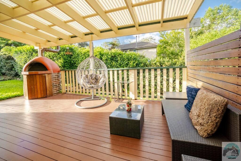 un patio con sofá y una silla en una terraza en Aircabin - Beecroft - Sydney - 3 Bed Holiday House, en Beecroft