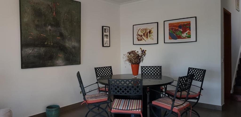 une salle à manger avec une table, des chaises et des peintures dans l'établissement Casa Melfer, à Sesimbra