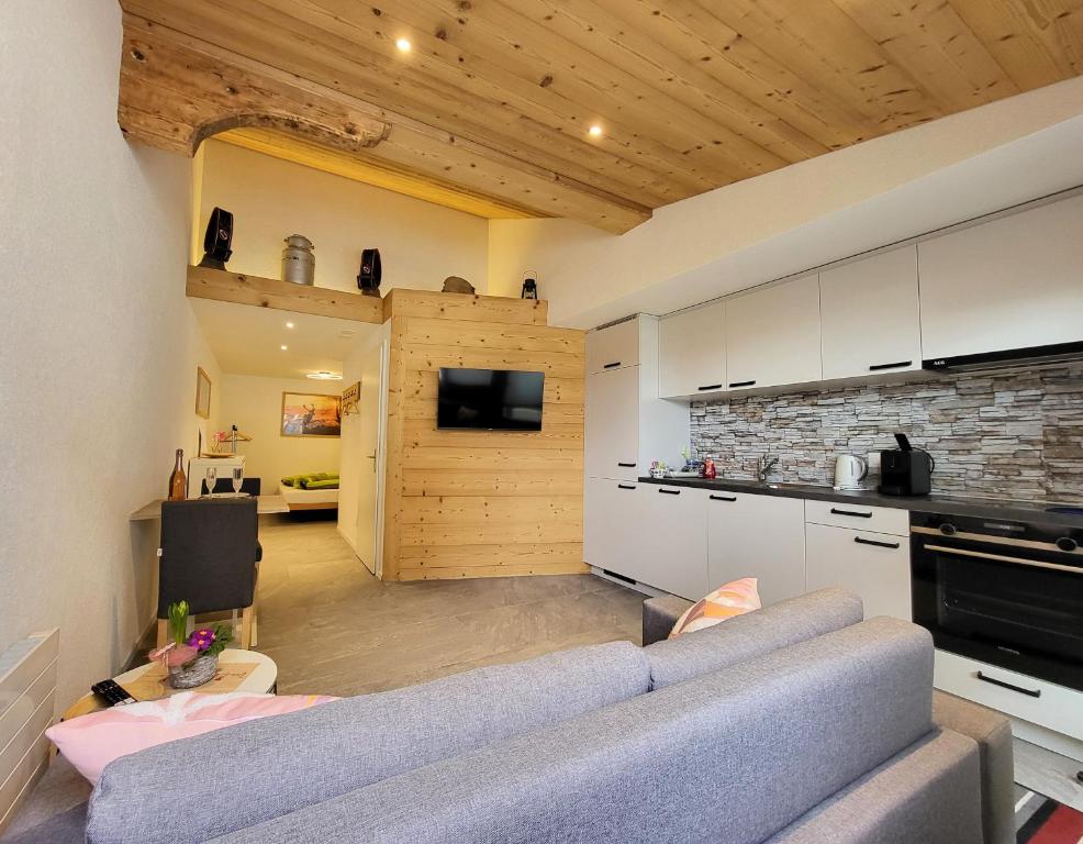 a living room with a gray couch and a kitchen at Chalet Lilo New Studio in Beatenberg