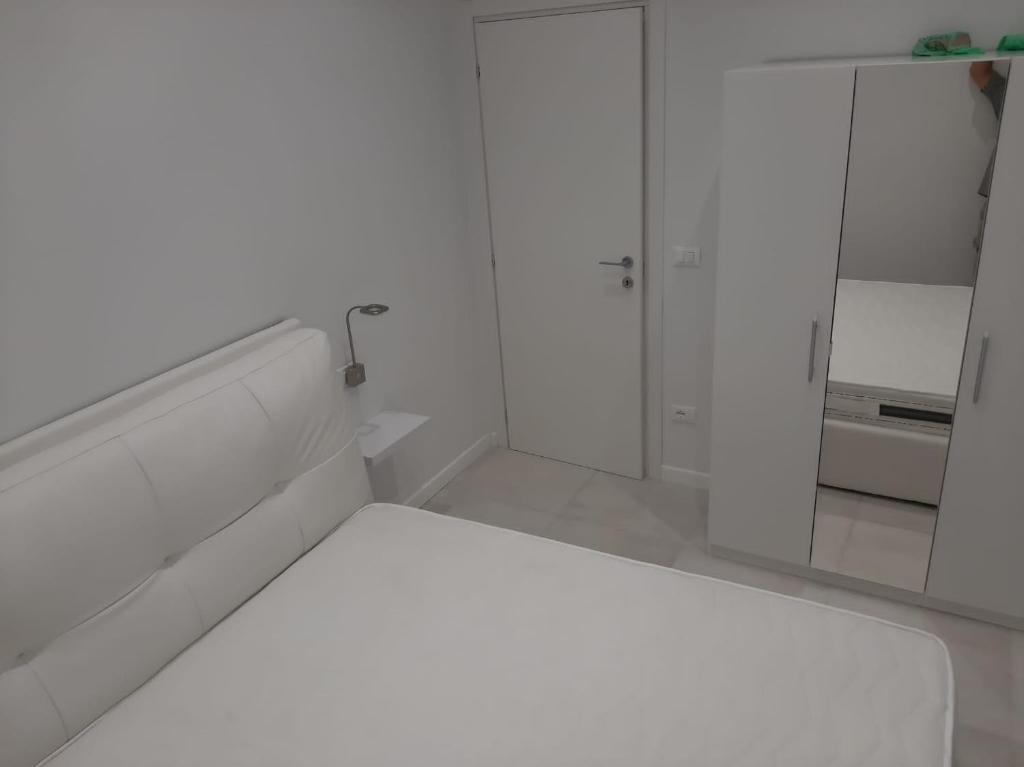 a white room with a bed and a cabinet at La Casa di Andre in Sanremo