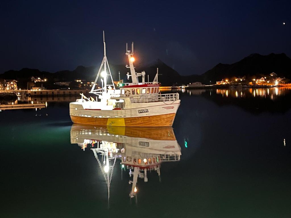 a boat sitting in the water at night at Sjøstrand Rorbuer v Børge Iversen AS in Ballstad